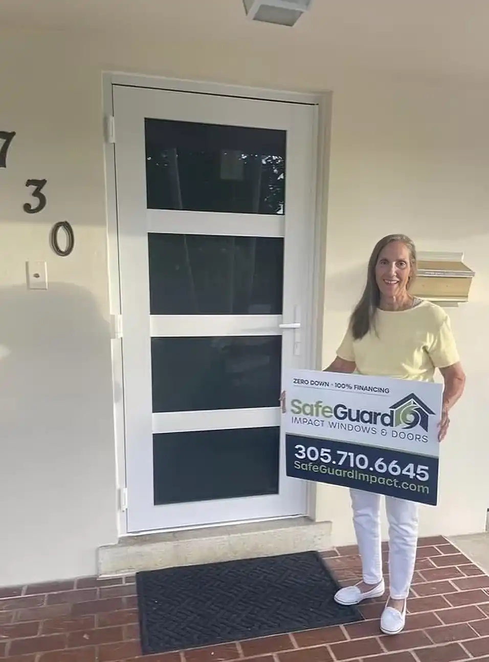 Happy homeowner beside new SafeGuard impact entry door South Florida