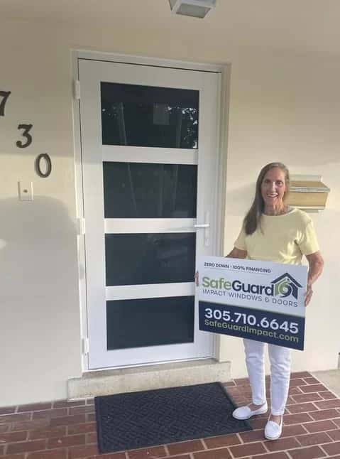 Homeowner holding SafeGuard sign beside new white impact door