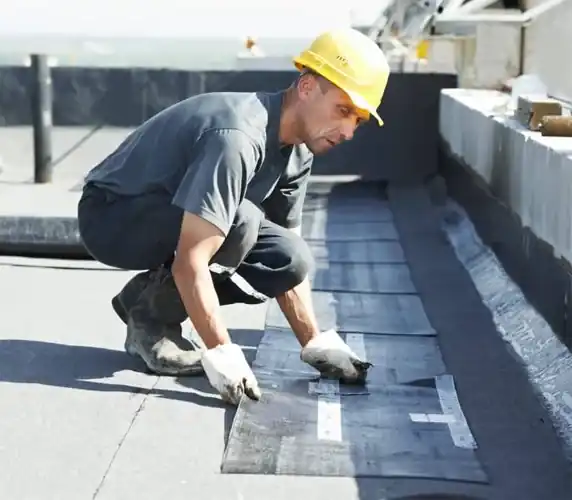 Roofer installing flat roof membrane on South Florida commercial building