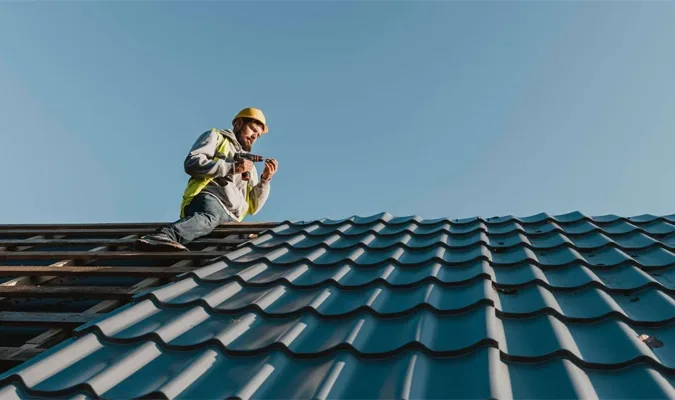 Roofer installing dark teal metal tile roof on South Florida home