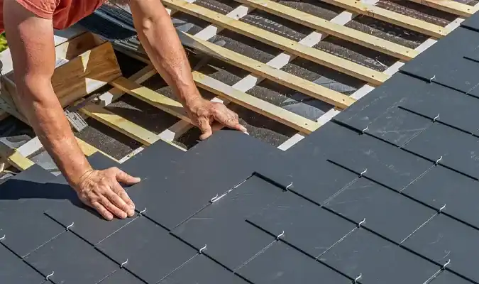 Roofer installing dark slate tiles over wood battens South Florida