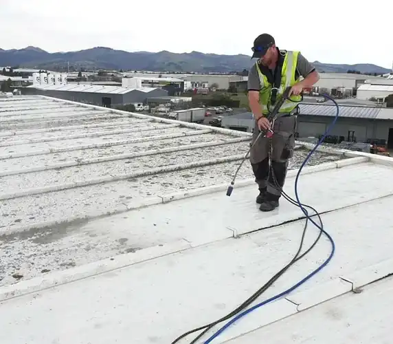 Roofer applying protective coating to flat commercial roof