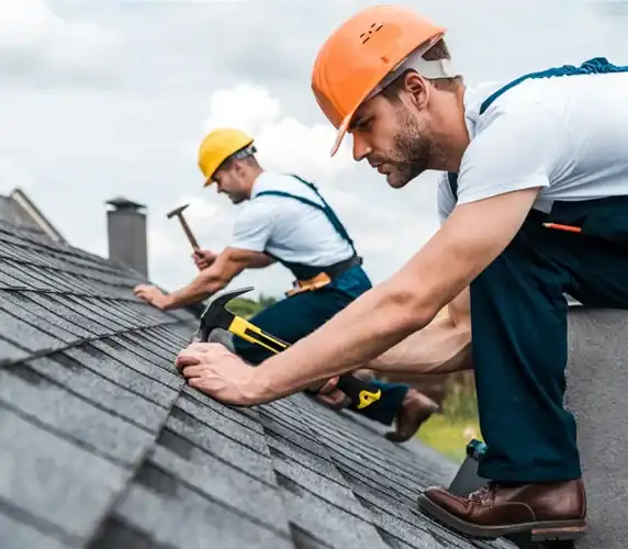Two roofers installing asphalt shingles on residential roof in South Florida