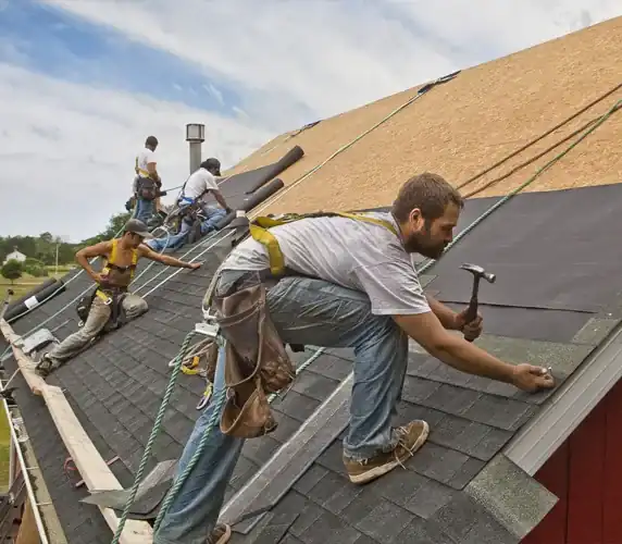 Roofing crew installing shingles and underlayment on residential home