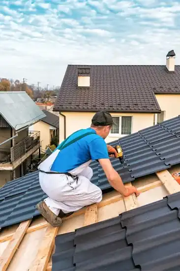 Roofer installing dark gray metal tiles on residential home