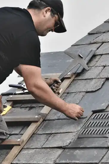 Roofer installing dark asphalt shingles on South Florida home