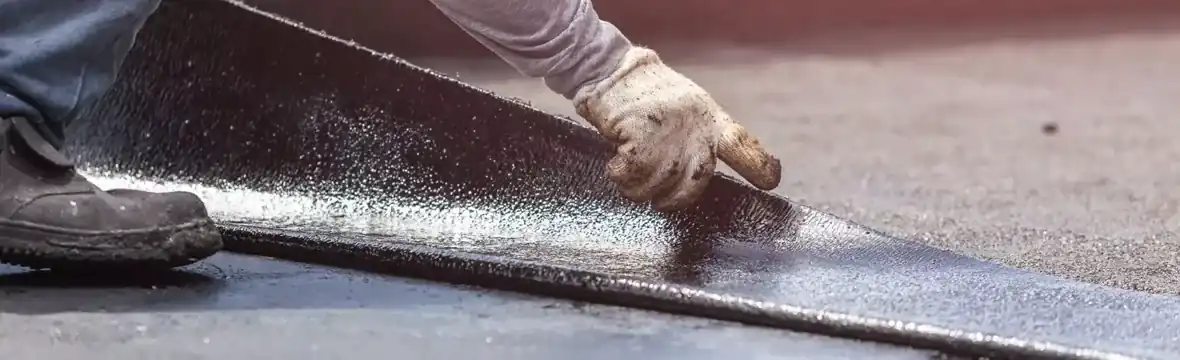 Roofer installing bitumen membrane on flat roof South Florida