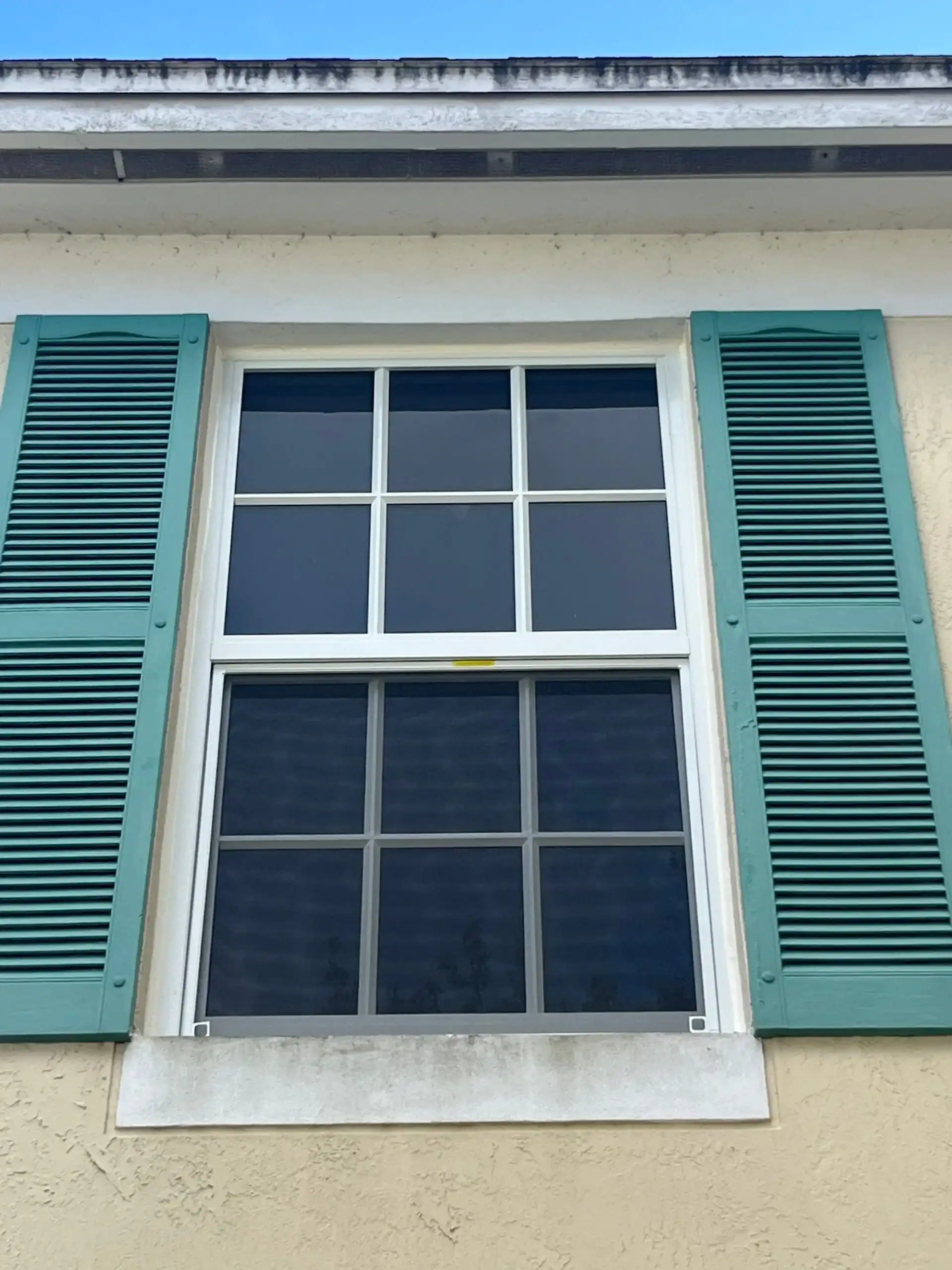 Impact double-hung window with teal shutters on Tamarac Florida home