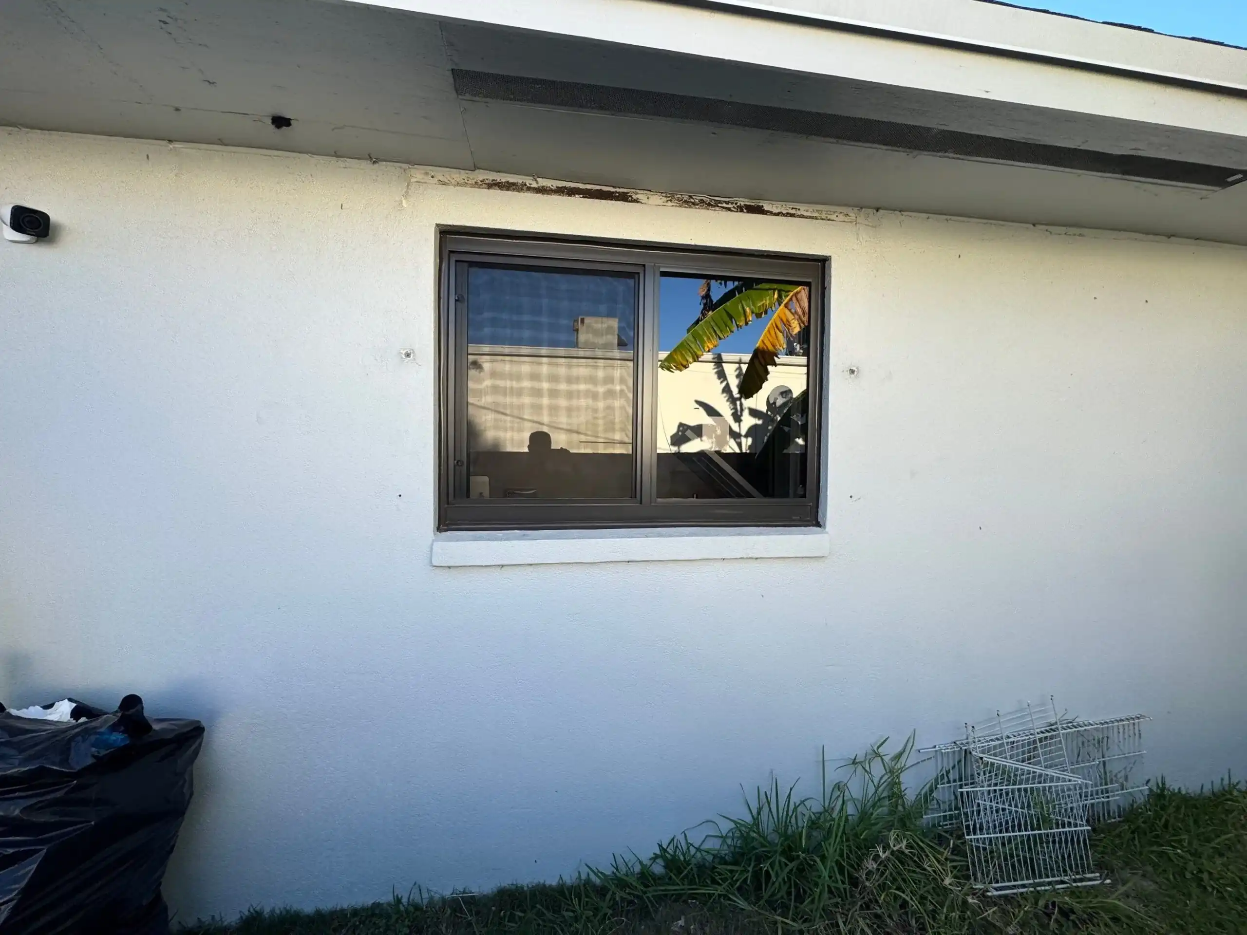 Dark bronze impact sliding window installed on white stucco home West Palm Beach