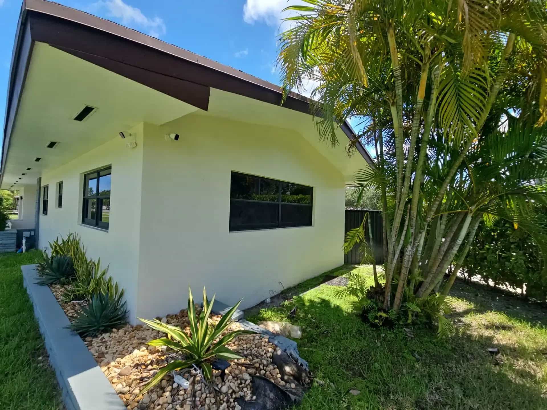 South Florida home with dark-framed impact windows and tropical landscaping