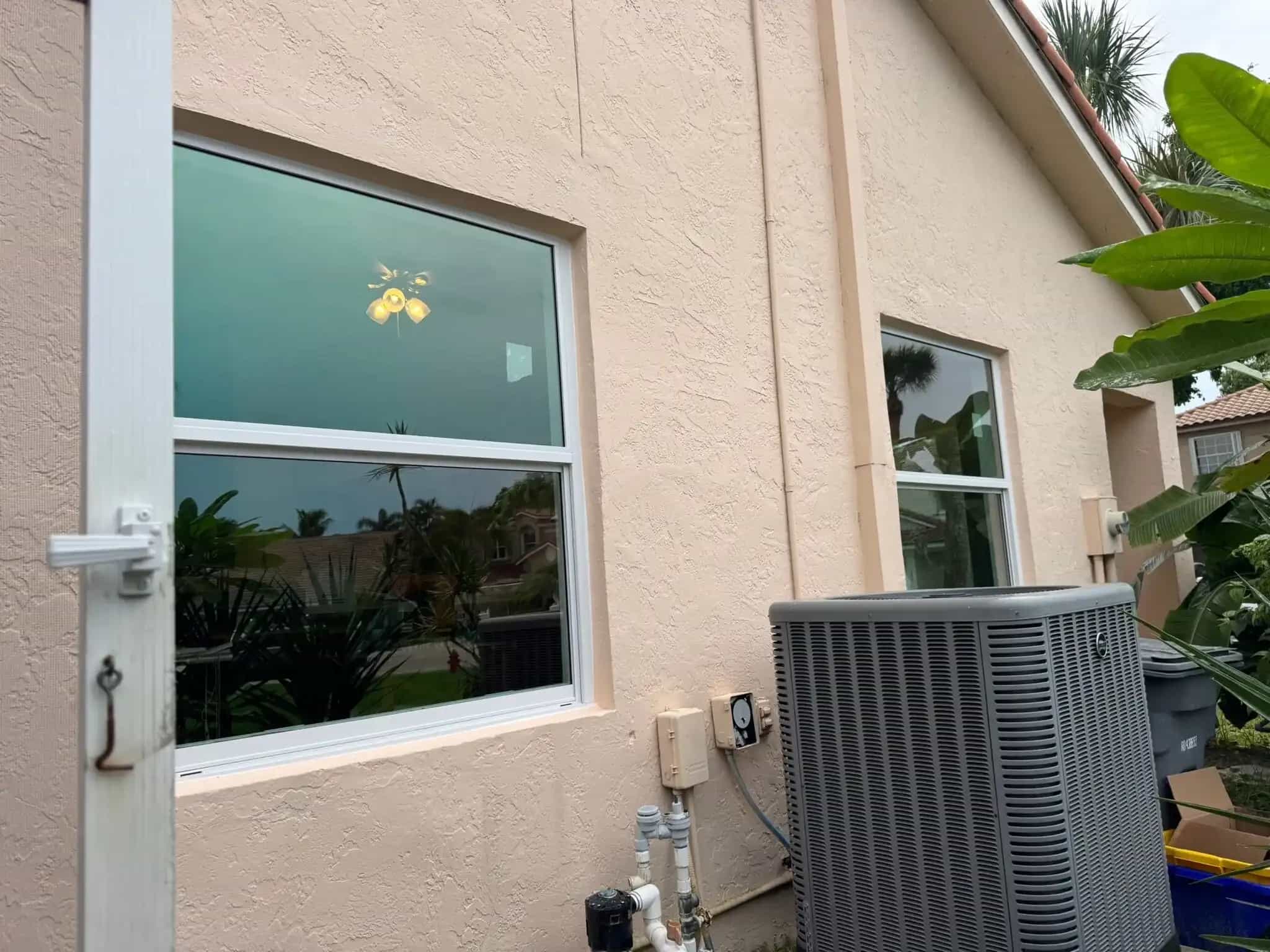 Impact windows with tinted glass on Boca Raton stucco home exterior