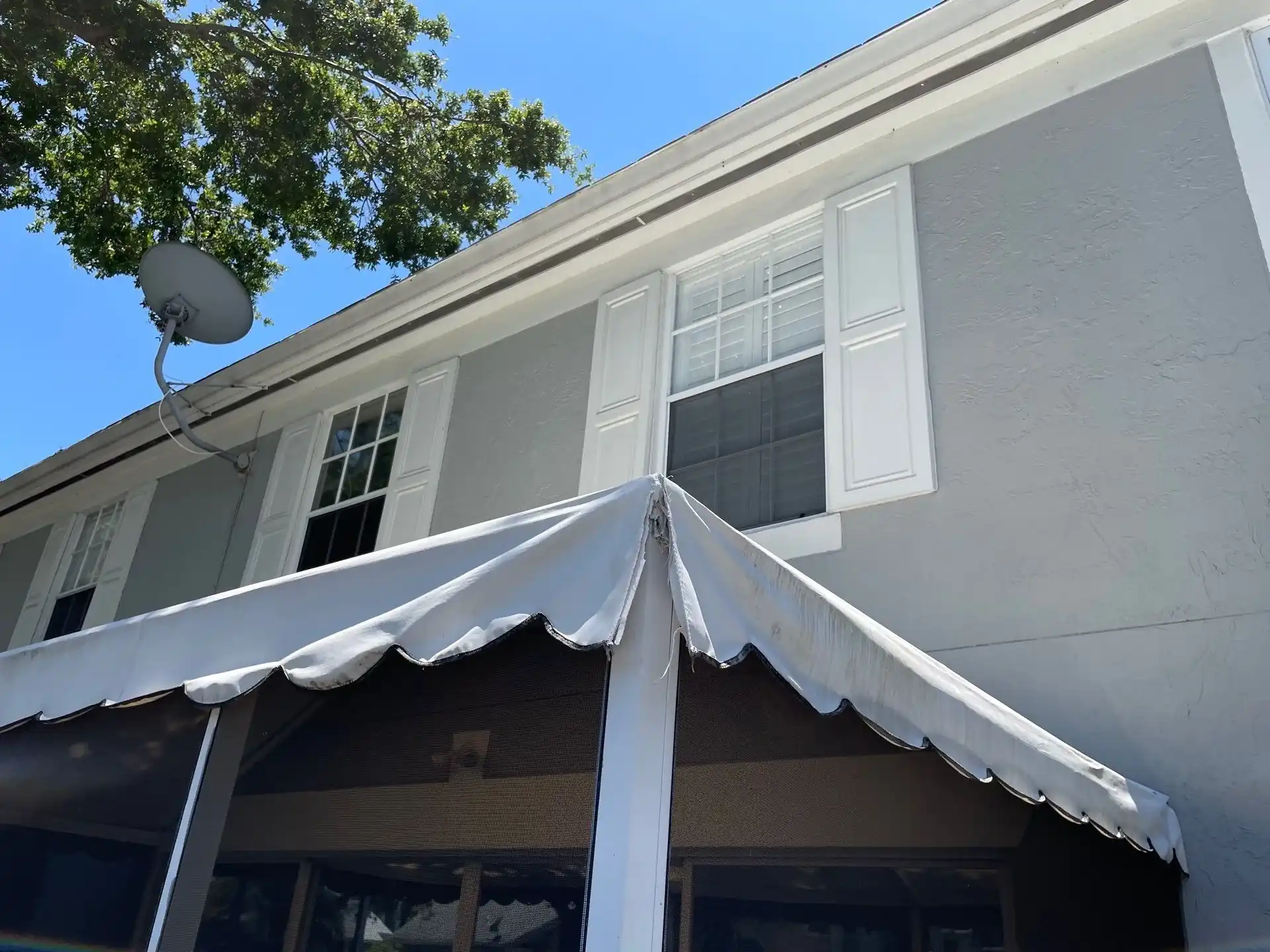 White impact windows with shutters on gray stucco South Florida home