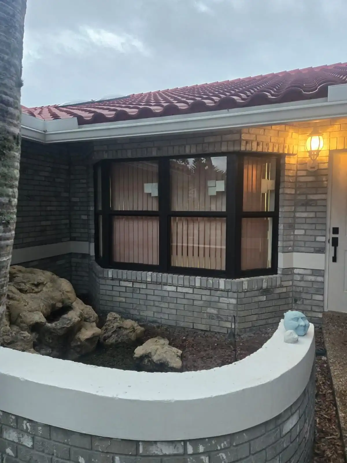 Black-framed impact window on brick home with red tile roof