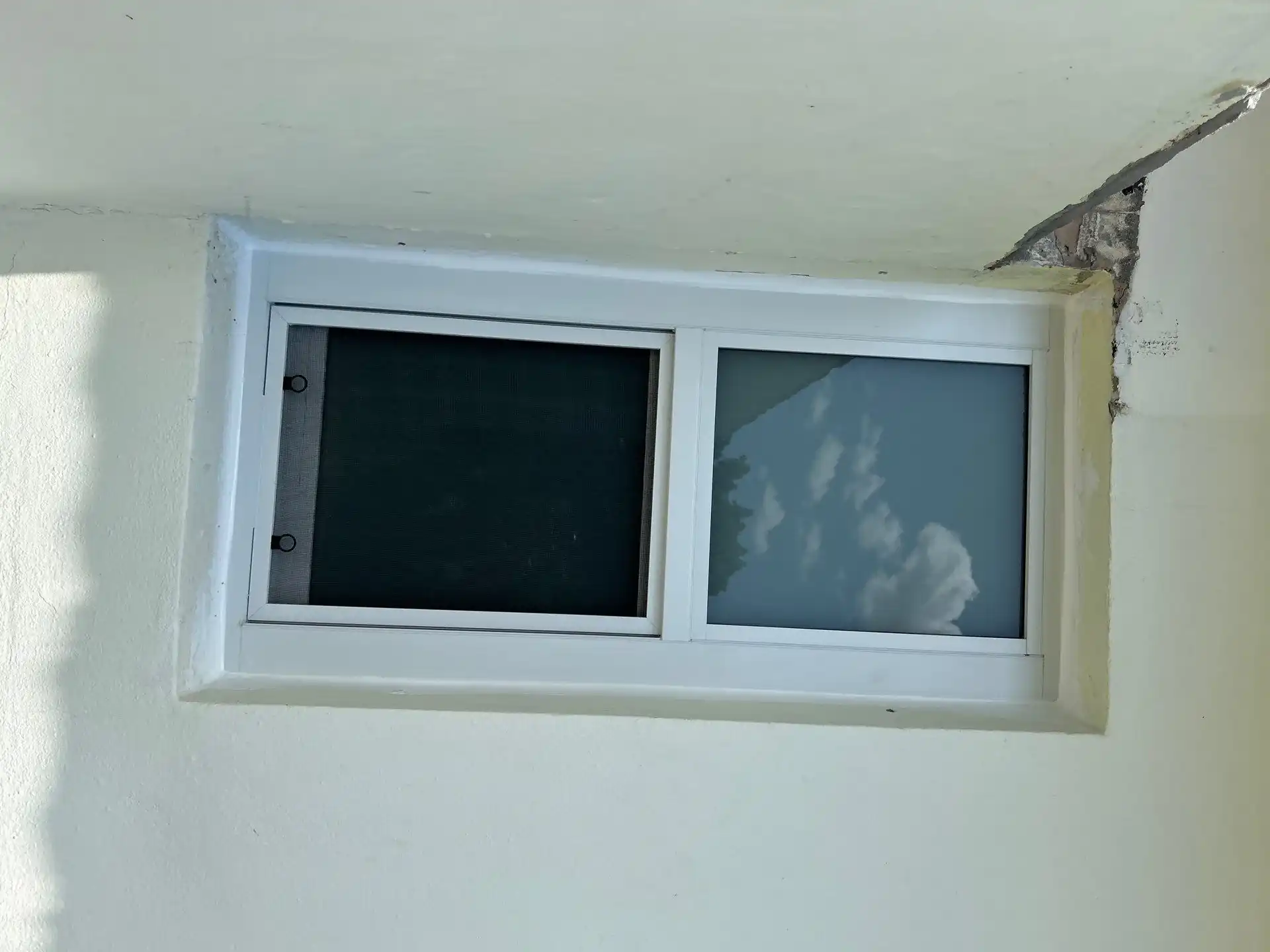 Small horizontal sliding impact window installed in Hialeah stucco home