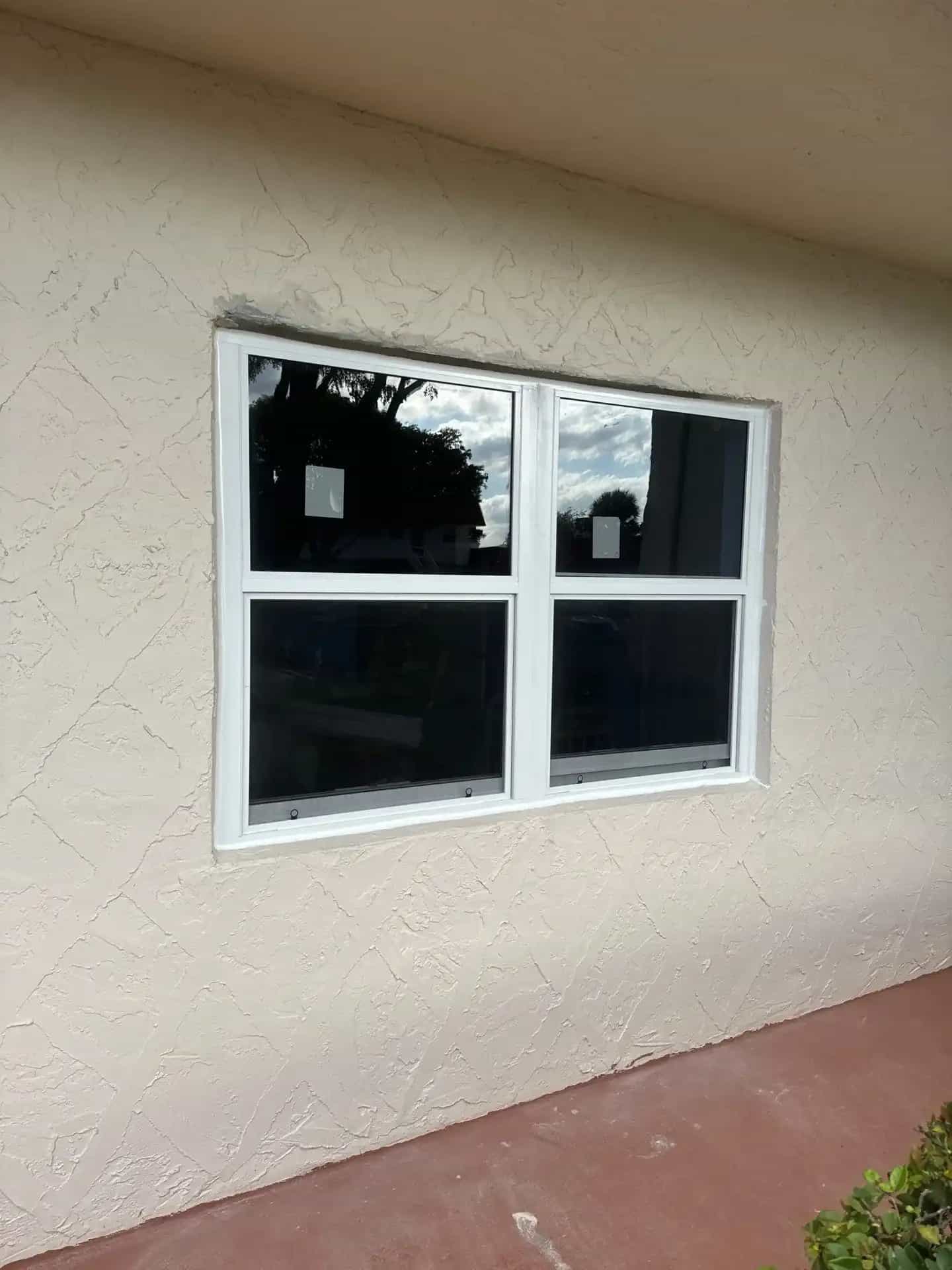 White frame impact window installed on stucco home exterior South Florida