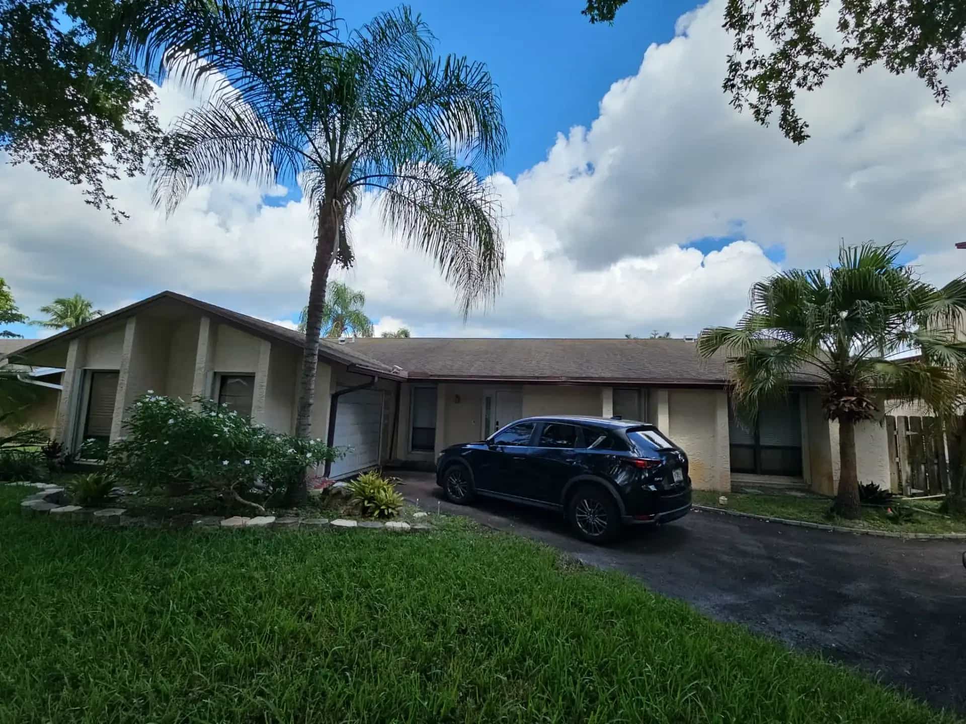 Single-story Cooper City Florida home with asphalt shingle roof and palms