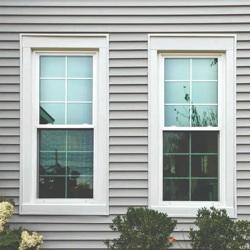 White double-hung impact windows with grid on gray vinyl siding